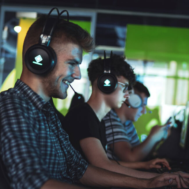 Gracz Basestack ze słuchawkami do gier uśmiecha się podczas grania w grę komputerową.